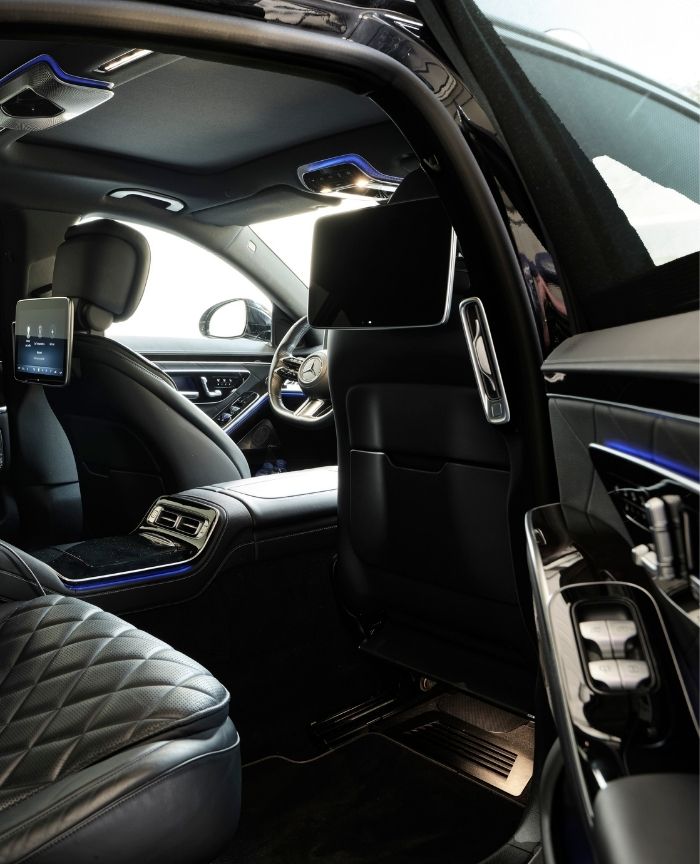 English: The luxurious and modern interior of a black Mercedes-Benz sedan, with quilted leather seats and digital screens Português: O interior de luxo de um sedan preto da Mercedes-Benz, com bancos de couro acolchoados e ecrãs digitais